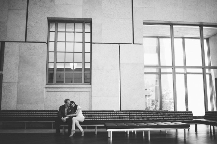 Couple sits inside a lobby during their engagement session at the Barnes Foundation in Philadelphia, PA. Captured by NJ wedding photographer Ben Lau.