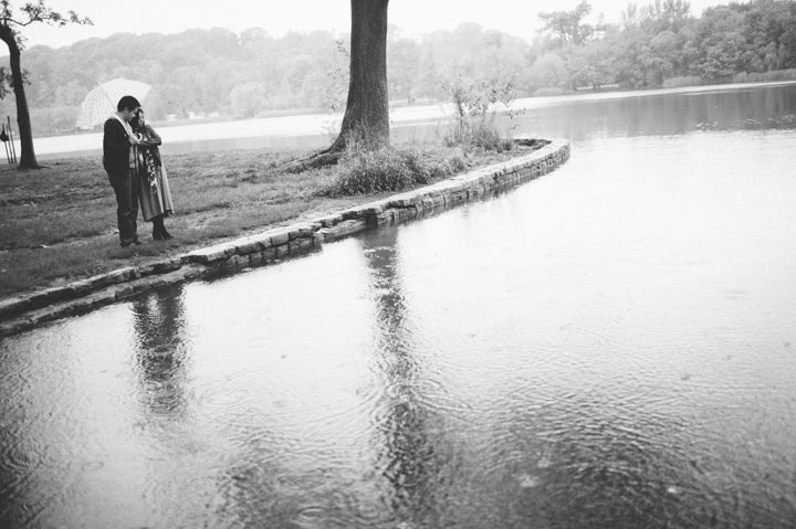 Couple poses with an umbrella by a lake during their rainy engagement session in Prospect Park with NYC wedding photographer Ben Lau.