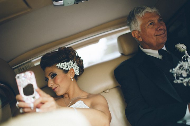 Bride takes a selfie while en route to her wedding ceremony at the Old Tappan Manor in Old Tappan, NJ. Captured by Northern New Jersey Wedding Photographer Ben Lau.