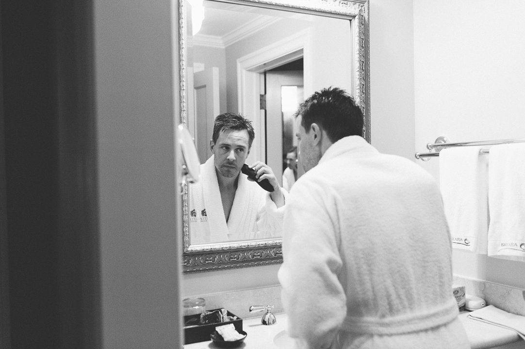Groom shaves in the mirror at the Castle on the Hudson in Tarrytown, NY. Captured by NYC wedding photographer Ben Lau.