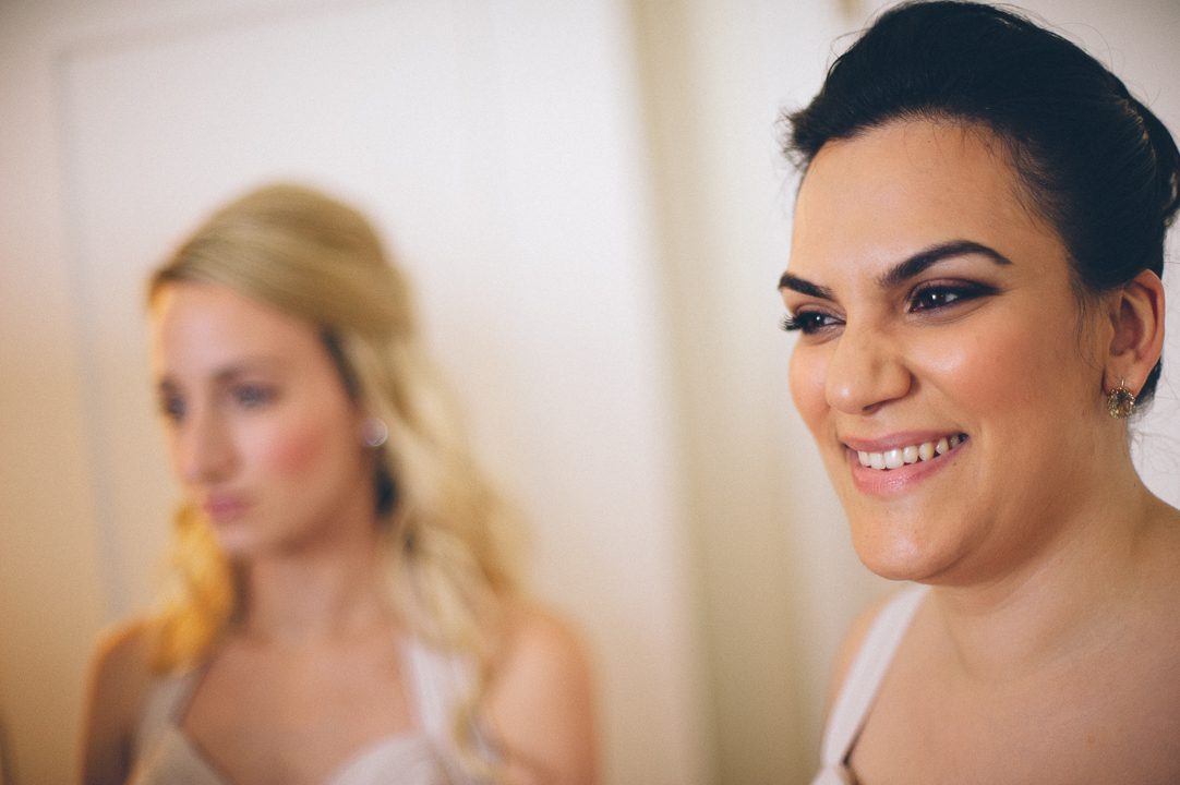 Maid of honor smiles at her sister on the morning of her wedding at the Castle on the Hudson in Tarrytown, NY. Captured by NYC wedding photographer Ben Lau.