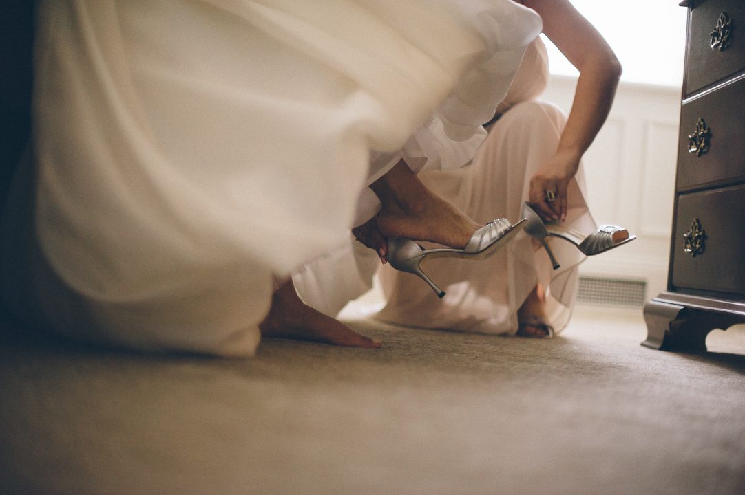 Bride puts on her shoes on the morning of her wedding at the Castle on the Hudson in Tarrytown, NY. Captured by NYC wedding photographer Ben Lau.