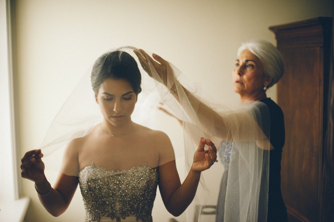 Mother of the bride helps her daughter into her veil on the morning of her wedding at the Castle on the Hudson in Tarrytown, NY. Captured by NYC wedding photographer Ben Lau.