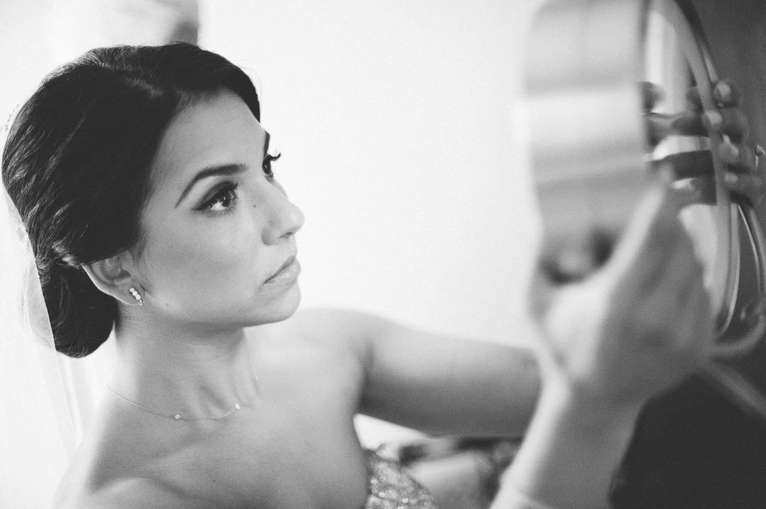 Bride checks herself in the mirror on the morning of her wedding at the Castle on the Hudson in Tarrytown, NY. Captured by NYC wedding photographer Ben Lau.