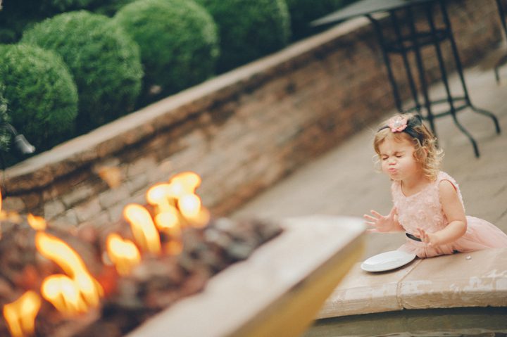 Flower girl plays by a fountain at the Stone House in Stirling Ridge. Captured by NJ wedding photographer Ben Lau.