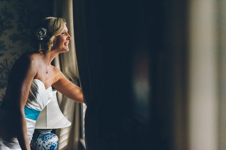 Bride looks out of the window at the Antrim 1844 Country House in Taneytown, MD. Captured by Baltimore wedding photographer Ben Lau.