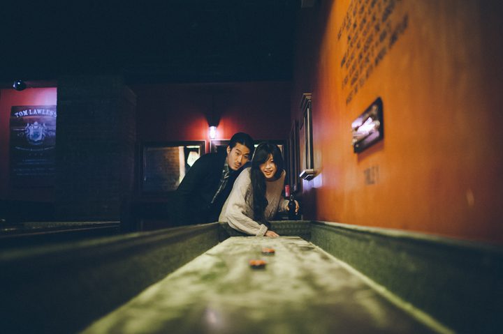 Michele and Bryan play shuffleboard during their engagement session in Williamsburg with NYC wedding photographer Ben Lau.