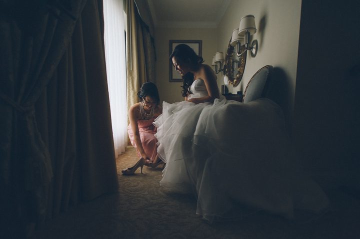Bride puts on her wedding shoes at the Ritz Carlton in San Francisco, CA. Captured by NYC wedding photographer Ben Lau.