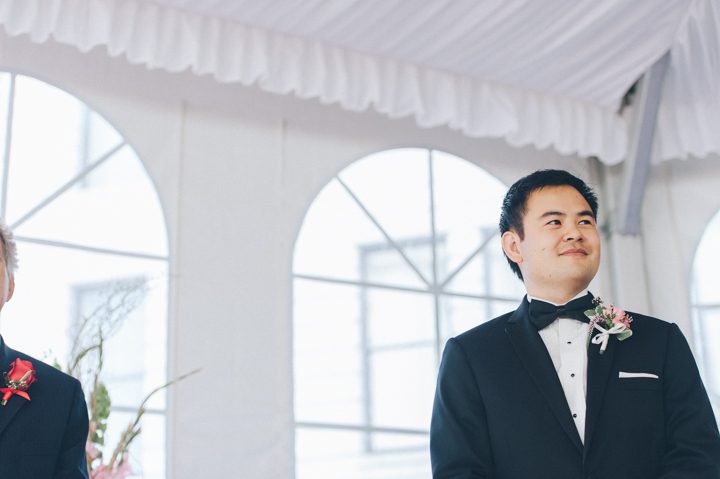 Groom reacts as his bride comes down the aisle during a wedding ceremony at the Ritz Carlton in San Francisco, CA. Captured by NYC wedding photographer Ben Lau.