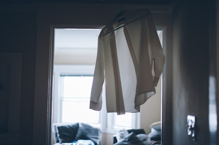 Wedding dress shirt hangs by the doorway at the Ritz Carlton in San Francisco, CA. Captured by NYC wedding photographer Ben Lau.