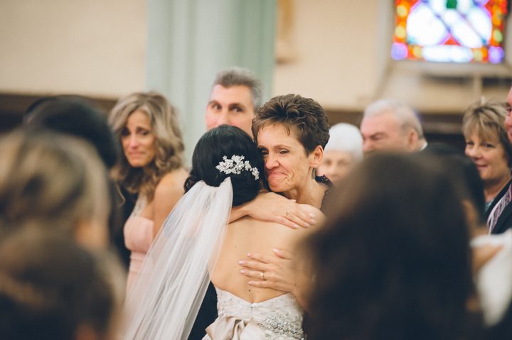 Bride hugs her mother-in-law during her St. Peter the Apostle Church wedding in New Brunswick, NJ. Captured by NJ wedding photographer Ben Lau.