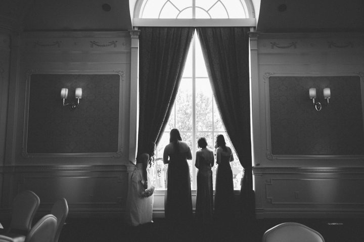 Bridesmaids look out of the window during a Westmount Country Club wedding ceremony in Woodland Park, NJ. Captured by awesome NJ wedding photographer Ben Lau.