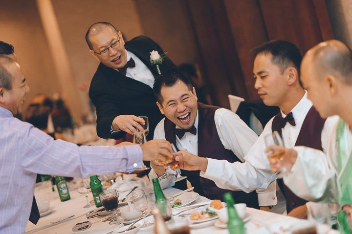 Groomsmen laugh during a wedding reception at China Garden in Rosslyn, Northern Virginia. Captured by NYC wedding photographer Ben Lau.