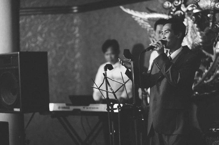 Guest sings during a wedding reception at China Garden in Rosslyn, Northern Virginia. Captured by NYC wedding photographer Ben Lau.