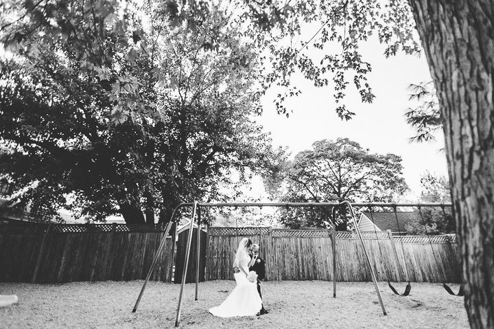 Bride and groom pose on a swing set in Clarendon, VA. Captured by NYC wedding photographer Ben Lau.