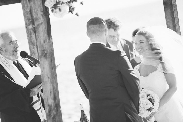 Bride smiles at her groom during their beach wedding ceremony at Westhampton Bath & Tennis in Westhampton, NY. Captured by NYC wedding photographer Ben Lau.