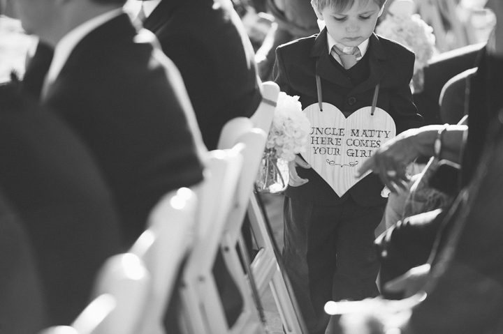 Ring boy with a sign during a beach wedding ceremony at Westhampton Bath & Tennis in Westhampton, NY. Captured by NYC wedding photographer Ben Lau.