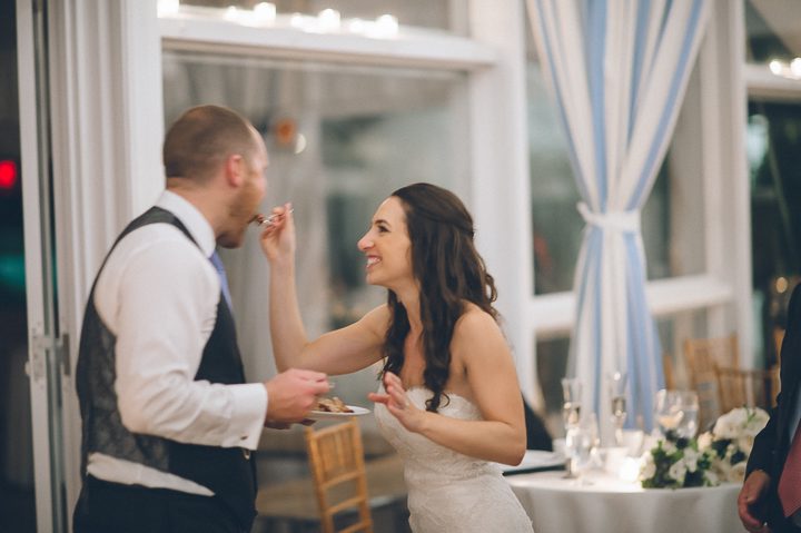 Bride feeds the groom cake during a reception at Oceanblue/Westhampton Bath & Tennis in Westhampton, NY. Captured by NYC wedding photographer Ben Lau.