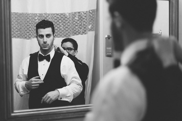 Groom fixes his shirt on the morning of his wedding day at the Belvedere Hotel in Baltimore, MD. Captured by NYC wedding photographer Ben Lau.