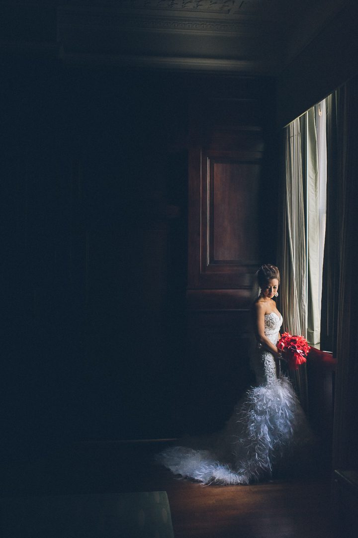 Bride poses by the window on the morning of her wedding at Hampton Inn in Downtown Baltimore. Captured by NYC wedding photographer Ben Lau.