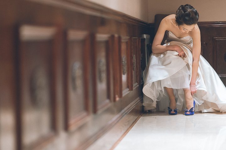 Bride puts on her shoes on the morning of her wedding day at The Estate at Florentine Gardens in River Vale, NJ. Captured by Northern NJ wedding photographer Ben Lau.