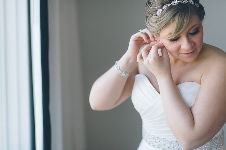 Bride puts on her earrings. McLoones Pierhouse Wedding in Long Branch, NJ. Captured by NYC wedding photographer Ben Lau.