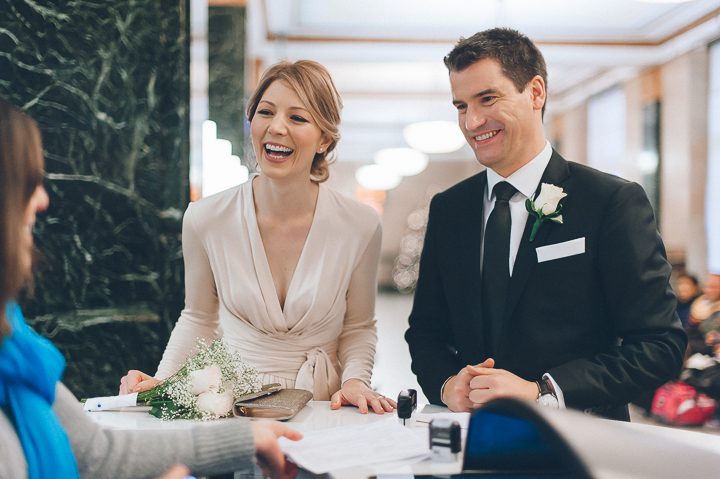 Bride and groom laugh while waiting in line at the NYC marriage bureau. New York City Hall wedding, captured by NYC wedding photographer Ben Lau.