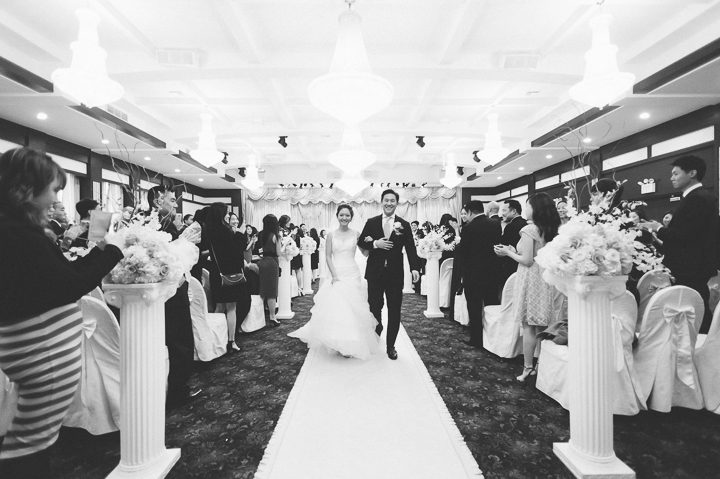 Bride and groom walk down the aisle together after their wedding ceremony at Dae Dong Manor in Flushing, NY. Captured by NYC wedding photographer Ben Lau.