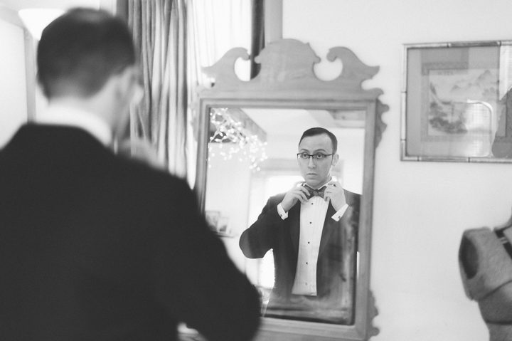 Groom ties his bow tie in preparation for his wedding day at Kirkpatrick Chapel in New Brunswick, NJ. Captured by Central Jersey Wedding Photographer Ben Lau.