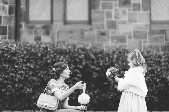 Bridesmaid hands flowers to flower girl in front of Kirkpatrick Chapel in New Brunswick, NJ. Captured by Central Jersey Wedding Photographer Ben Lau.