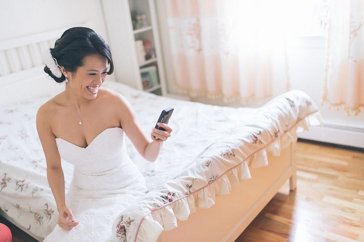 Bride watches Chinese Wedding door games from her phone. Captured by NYC wedding photographer Ben Lau.