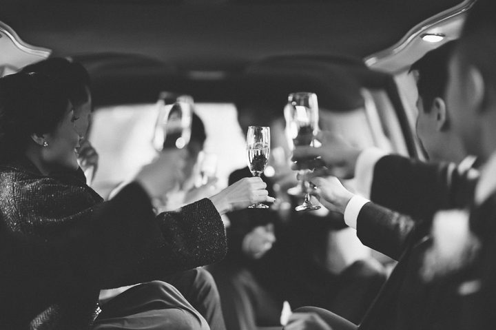 Champaign glass clink during a limo ride. Captured by NYC wedding photographer Ben Lau.