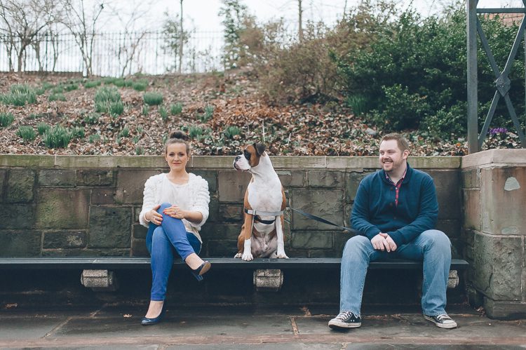 Couple sits on a bench with their dog during their engagement session in Central Park. Captured by NYC wedding photographer Ben Lau.
