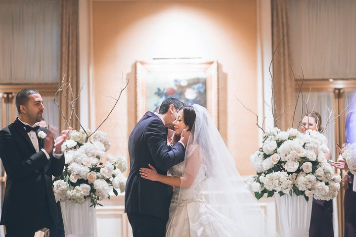 Bride and groom kiss during their wedding ceremony at the Essex House in NYC. Captured by NYC wedding photographer Ben Lau.