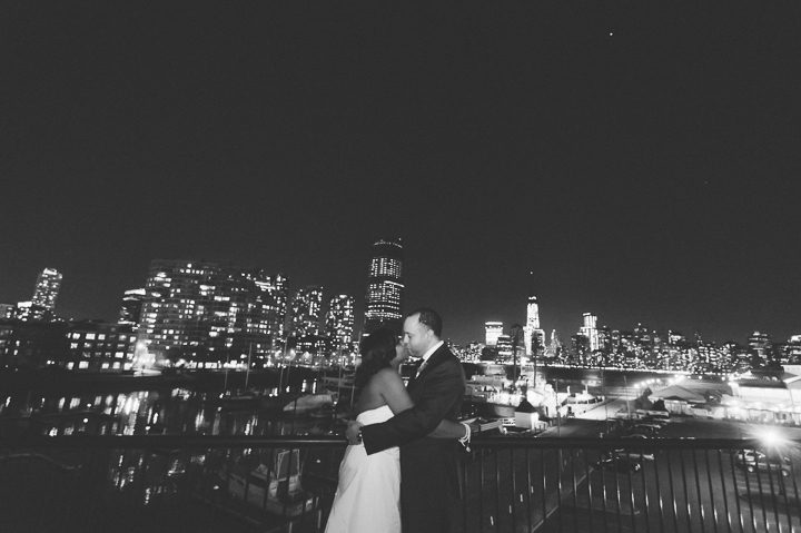 Bride and groom take a photo with the NYC skyline from the Maritime Parc in Jersey City, NJ. Captured by NYC wedding photographer Ben Lau.
