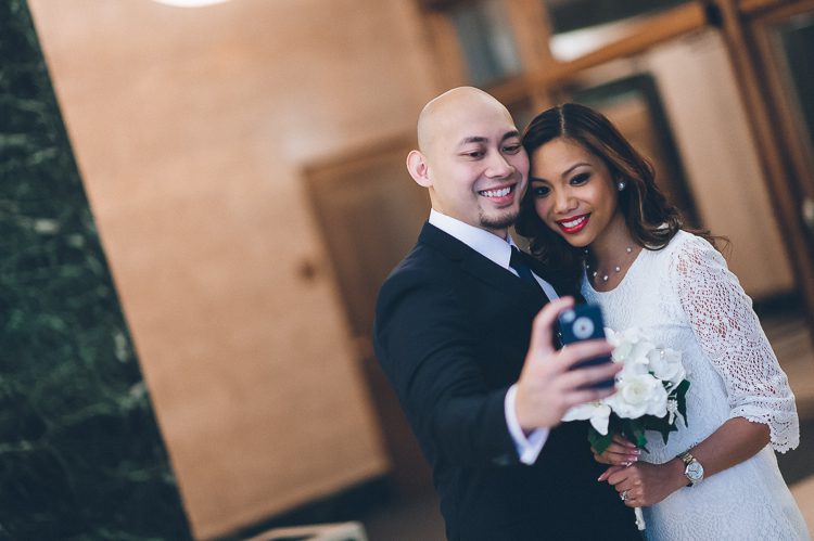 Jen and Edwin take a selfie at the marriage bureau in NYC. Captured by NYC City Hall wedding photographer Ben Lau.