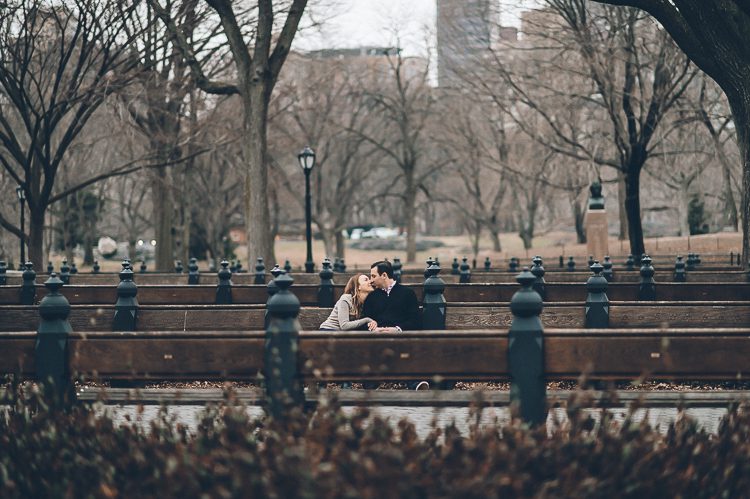 Couple sits on empty benches, during their engagement session in Central Park, with NYC wedding photographer Ben Lau.
