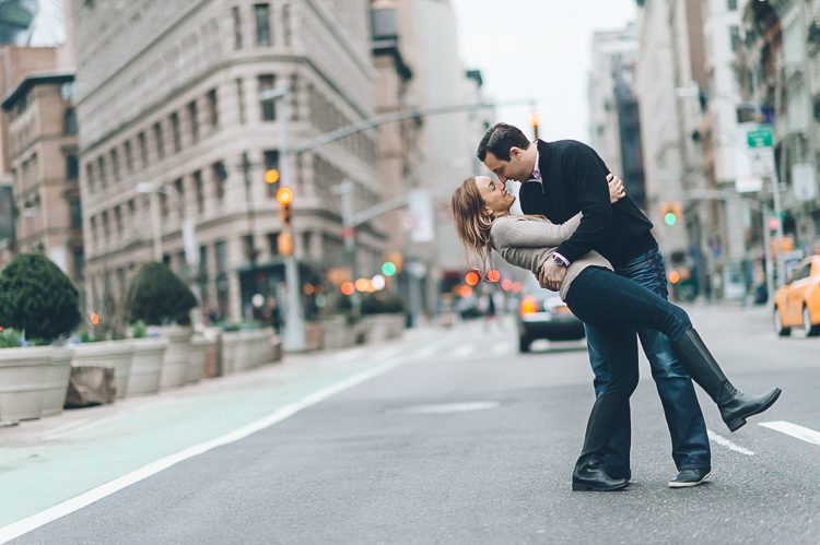 Guy dipping girl, during their engagement session in the Flat Iron District, with NYC wedding photographer Ben Lau.