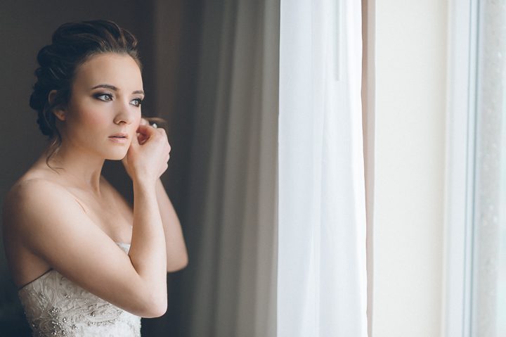 Bride puts on her earrings on the morning of her wedding at the Franklin Institute in Philadelphia. Captured by NYC wedding photographer Ben Lau.