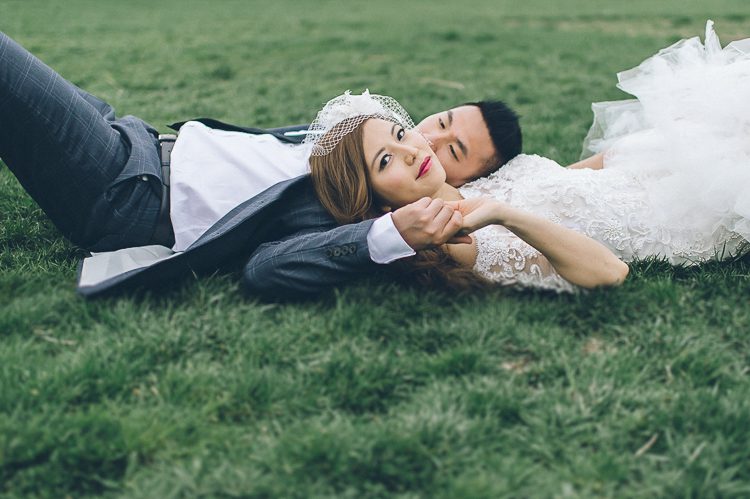Couple lies on the grass during their wedding photo session with NYC wedding photographer Ben Lau.