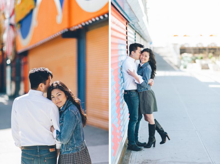 Couple pose against an orange gate during their engagement session in Coney Island. Captured by NYC wedding photographer Ben Lau.