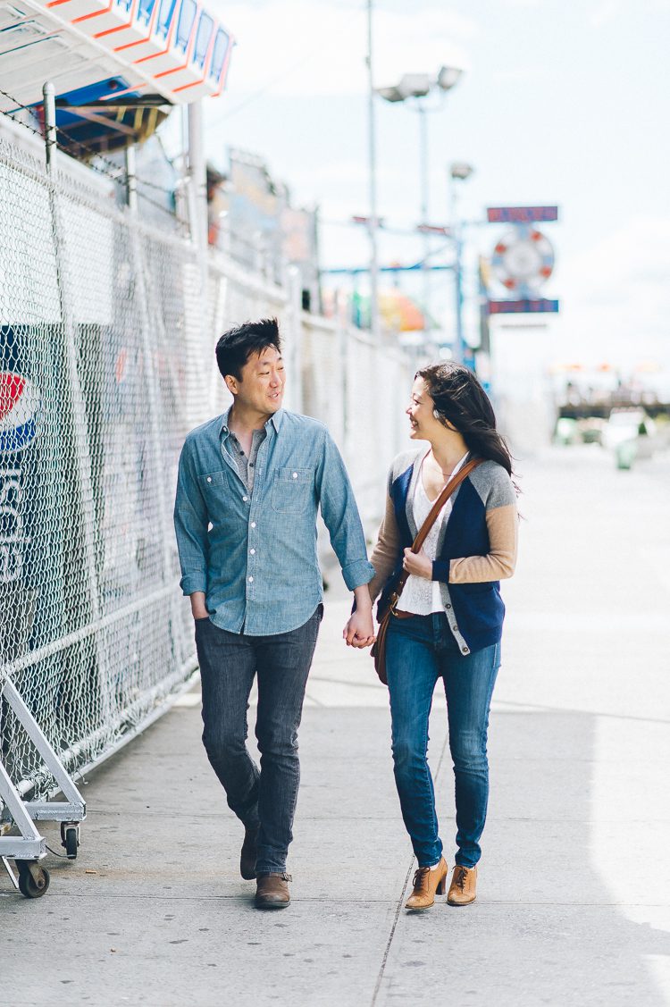 Couple stroll along the sidewalk at Coney Island. Captured by NYC wedding photographer Ben Lau.