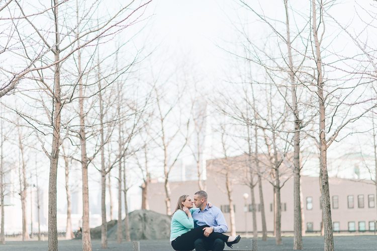 Couple sits on a bench during their engagement session in Hoboken, NJ. Captured by NJ wedding photographer Ben Lau.