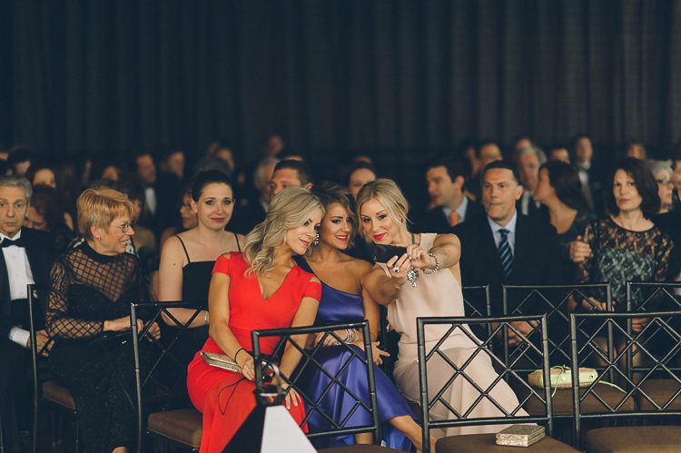 Guests take a selfie during a wedding ceremony at Pier 60 and the Light House. Captured by NYC wedding photographer Ben Lau.