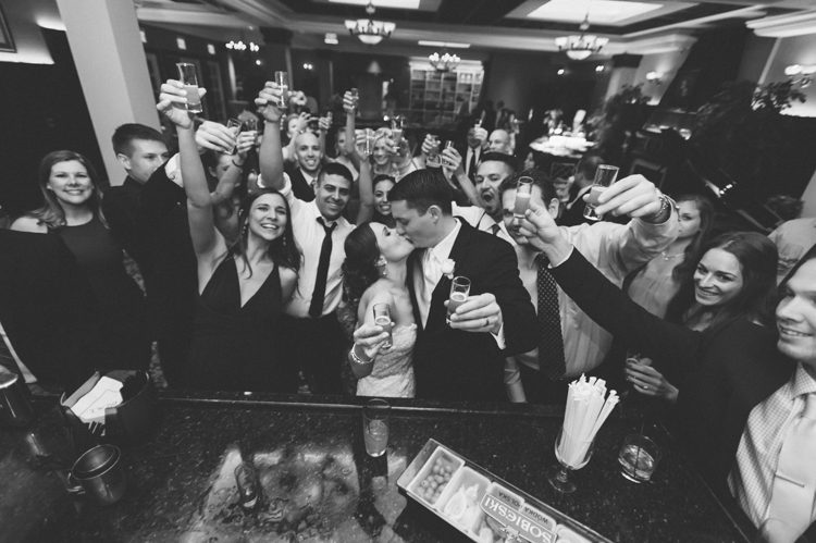 Bride and groom share a kiss at the bar during their wedding at The Palace at Somerset Park. Captured by Northern NJ wedding photographer Ben Lau.