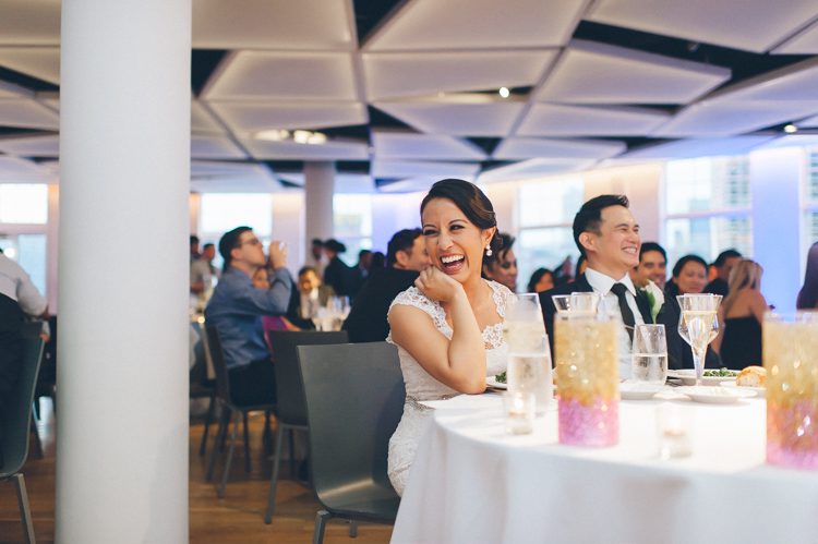 Bride laughs during toasts during her wedding reception at Maritime Parc in Jersey City, NJ. Captured by NYC wedding photographer Ben Lau.