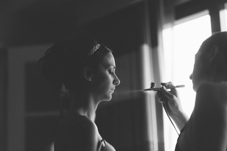 Bride gets airbrush make up on the morning of her wedding at the Liberty House in Jersey City, NJ. Captured by awesome NJ wedding photographer Ben Lau.