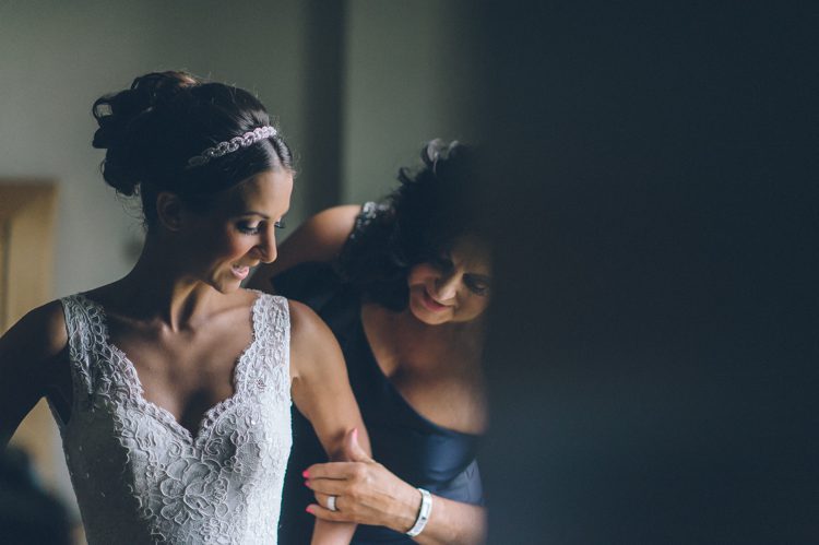 Mother of the bride helps her daughter with her dress on the morning of her wedding at the Liberty House in Jersey City, NJ. Captured by awesome NJ wedding photographer Ben Lau.