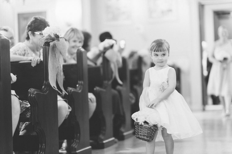 Flower girl notices the camera during a wedding ceremony at St. Catherines Church in Spring Lake Heights. Captured by North Jersey wedding photographers at Ben Lau Photography.