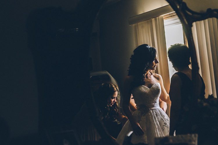 Bride puts on her dress on morning of her Patriot Hills wedding in Stony Point, NY. Captured by NYC wedding photographer Ben Lau Photography.